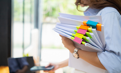 person carrying a stack of papers 