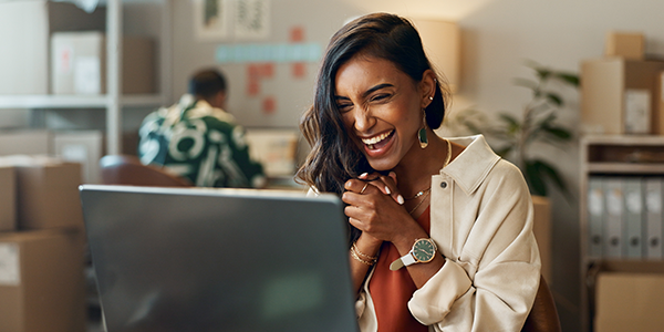 woman laughing looking at a desktop computer screen