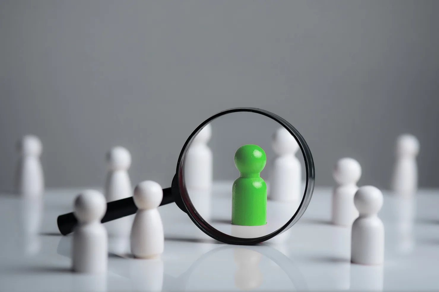 vendor selective board game pieces in white with green piece highlighted by magnifying glass