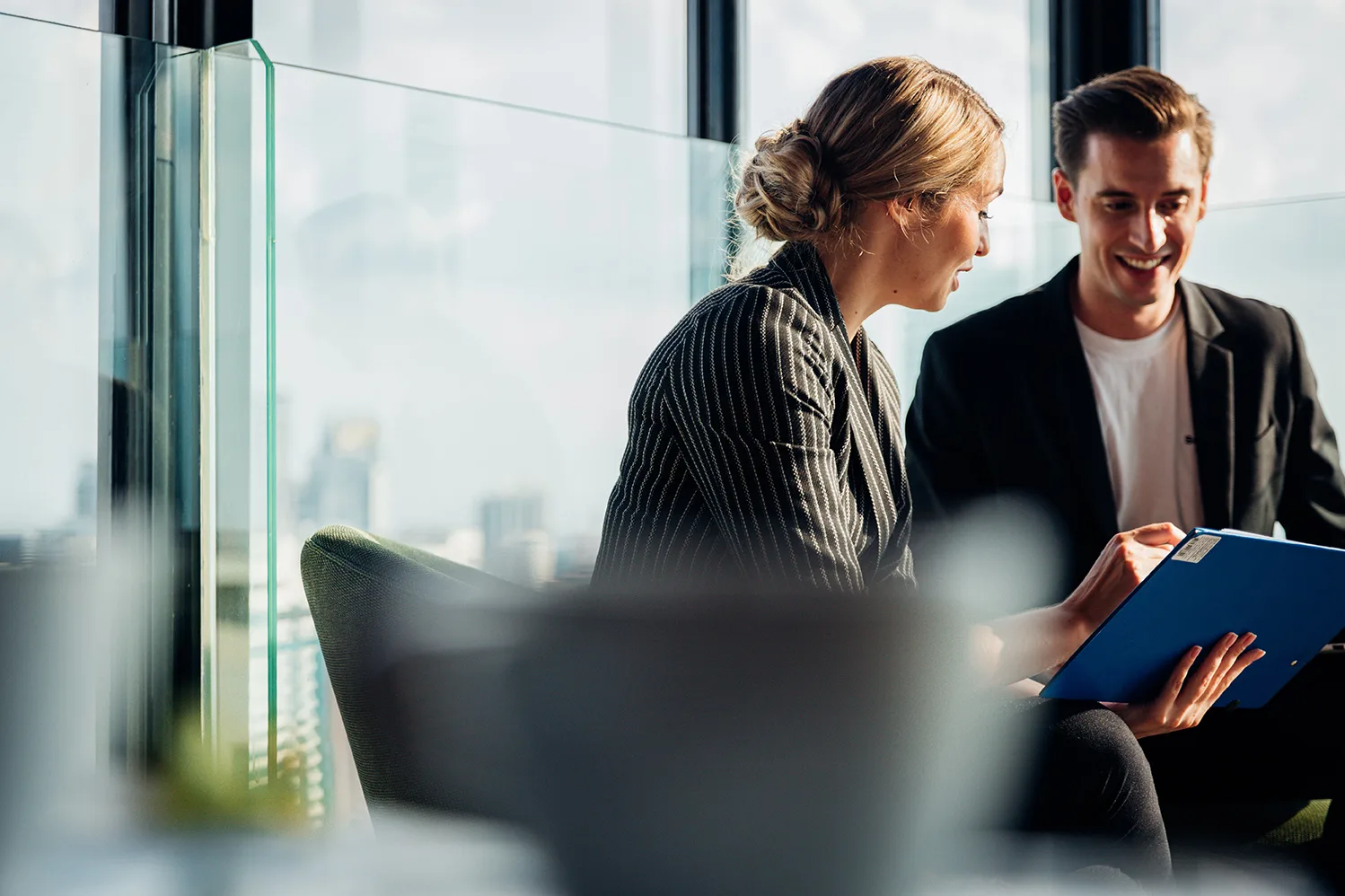 business woman and man in corporate setting looking at laptop device